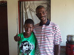 Margaret at home with Nico( Nicodemus) her brother in law who cares for her. Here they wear new T shirts which we bought for them. They are to start going to church